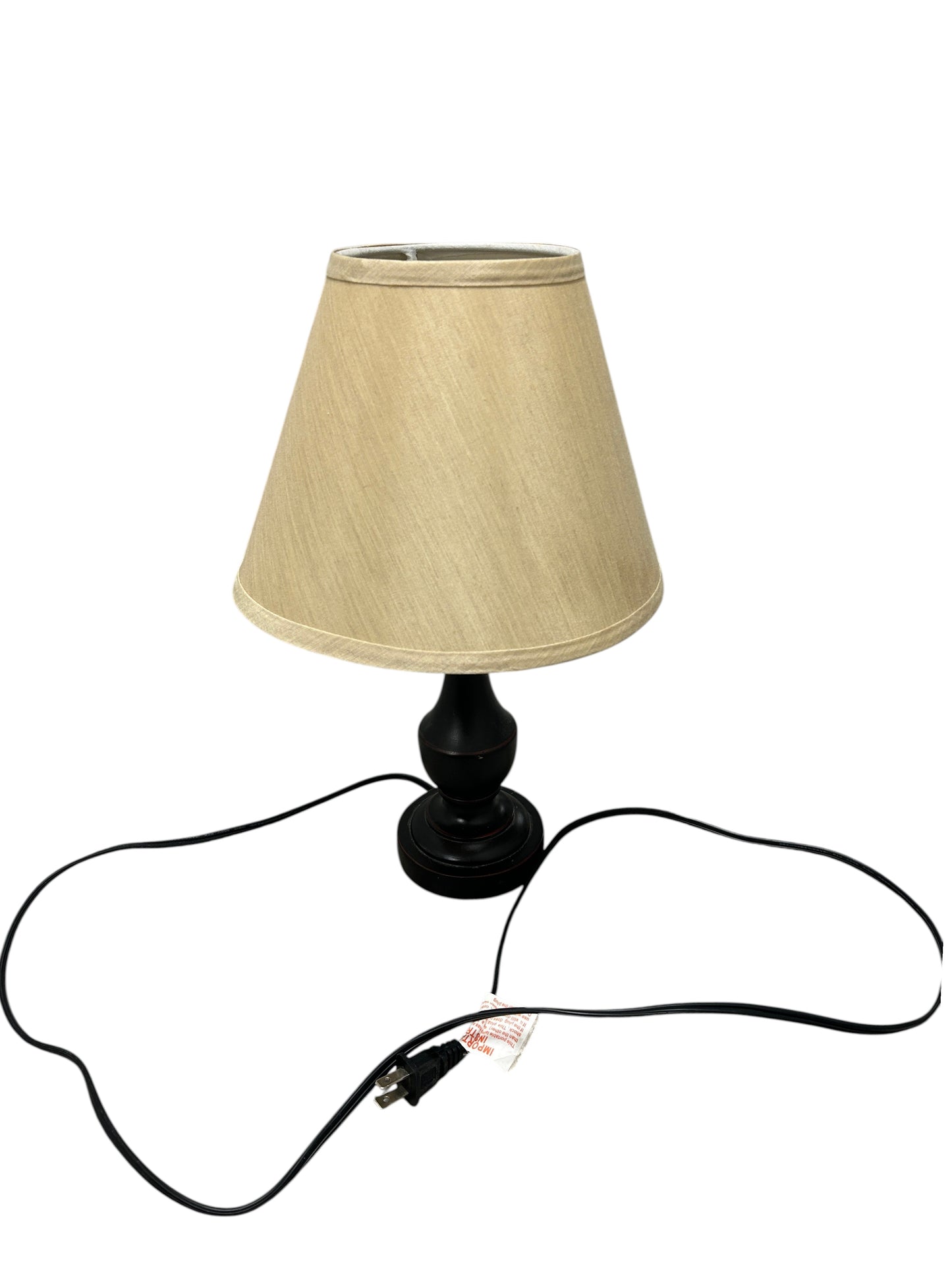 A table lamp with a black ceramic base and beige linen shade.