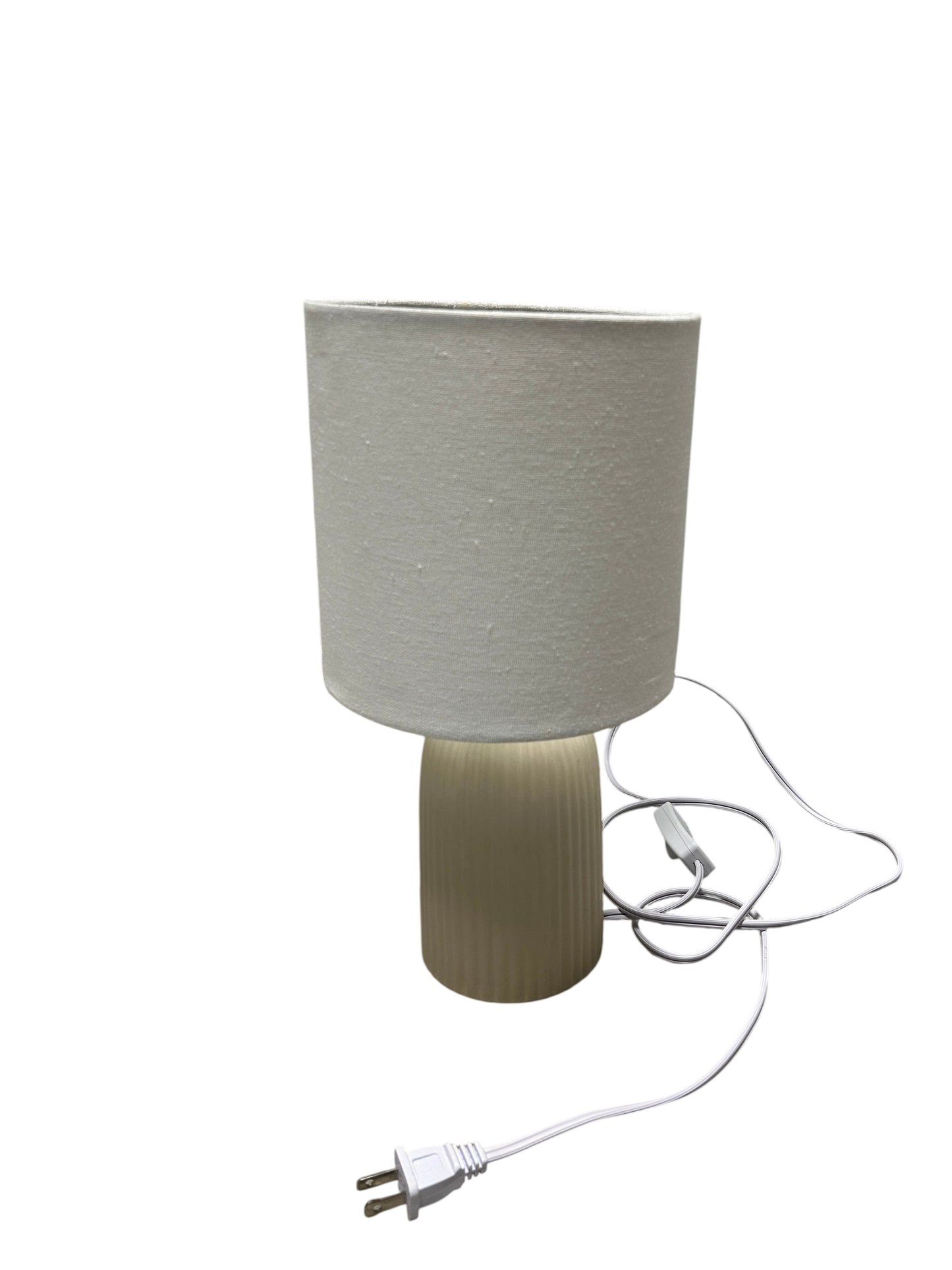 A cream table lamp with a ribbed ceramic base.
