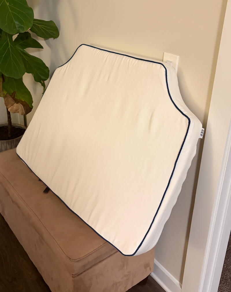 Room 422 twin white headboard with navy blue piping trim along the edges.